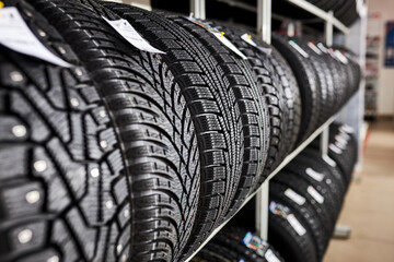 Naklejka na ściany i meble close-up new tires in the auto repair service center, brand new winter tires with a modern tread isolated. selective focus. tire stack background.winter season, no people