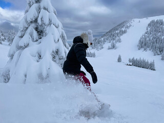 CLOSE UP: Young woman shreds fresh powder while snowboarding in backcountry.