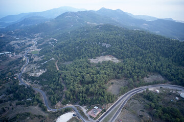 Aerial view of the mountains landscape in the morning. Road and green mountain forest. View from above.