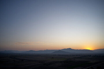 Aerial view of mountain valley at sunset. Summer farmland under sunset or sunrise sky and fog. A foggy evening on a picturesque meadow.
