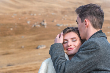 Beautiful young couple hugs high in the mountains in autumn. Relationship, travel and tourism concept