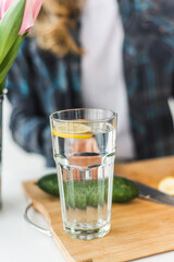 Homemade lemonade with cucumber and lemon is on a white table in the kitchen. Detox and diet food