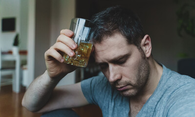 Fototapeta na wymiar Exhausted drunk man with glass of whiskey. Alcoholism concept.