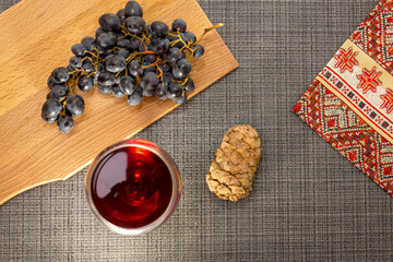 grapes and red wine with a cedar cone on a gray table