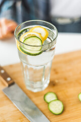 Homemade lemonade with cucumber and lemon is on a white table in the kitchen. Detox and diet food