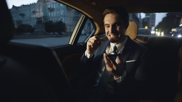 Angry business man swearing in voice chat on mobile phone in dark car.