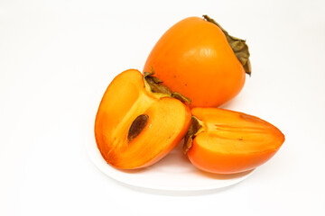 Persimmon fruits on plate white background. Two ripe sweet persimmons.