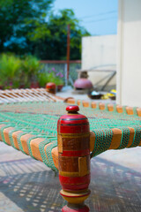 Bokeh style photo of charpai desi Indian Pakistani traditional bed made of woven rope mesh with beautiful red legs.