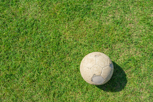 Old soccer ball on green grass of soccer field.