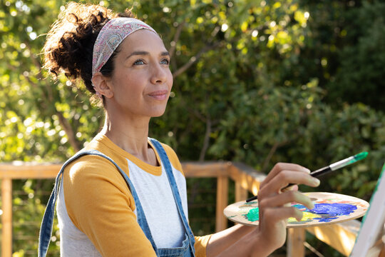 Caucasian woman painting picture outdoors on sunny day
