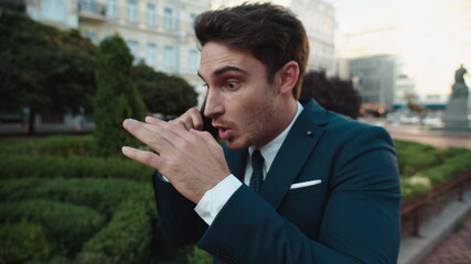 Portrait of aggressive male professional swearing on cellphone in city walk.