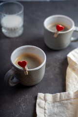 two cups of coffee with hearts attached and glass of milk on the table. Selective focus. Copy space for a text.