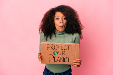 Young african american curly woman shrugs shoulders and open eyes confused.