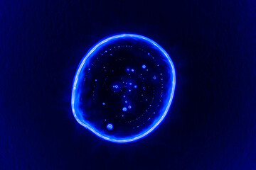 Clear transparent liquid gel dark blue drop or smear with neon light blue flare isolated on dark blue background. Top view. Virus protection or cosmetics concept. Serum texture