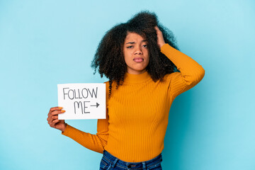 Young african american curly woman holding a follow me placard being shocked, she has remembered...