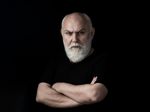 Serious Senior Man Looking At Camera Isolated On Black. Closeup Low Key Studio Portrait Of Gray Hair Old Man Looking At The Camera At Studio.