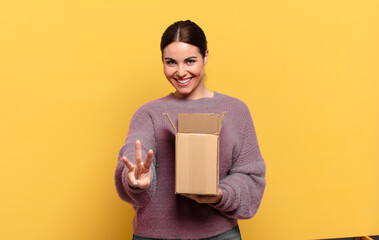 young pretty woman smiling and looking friendly, showing number three or third with hand forward,...