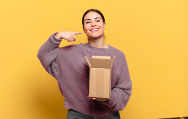 young pretty woman smiling confidently pointing to own broad smile, positive, relaxed, satisfied...