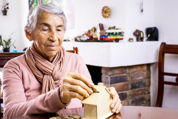 Closeup of a hand of a senior woman sitting at her home saving money