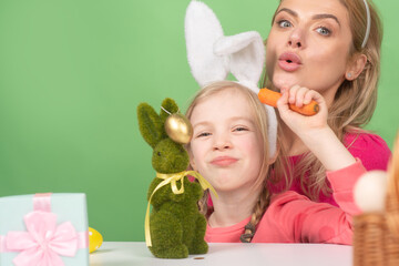 Family Easter. Mother and daughter with painting eggs. Cute little child girl is wearing bunny ears.