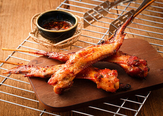 Grilled chicken wings seasoning with herbs on brown wooden cutting board
