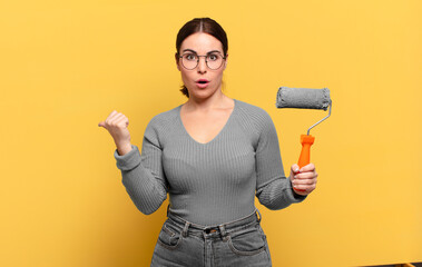young pretty woman looking astonished in disbelief, pointing at object on the side and saying wow,...