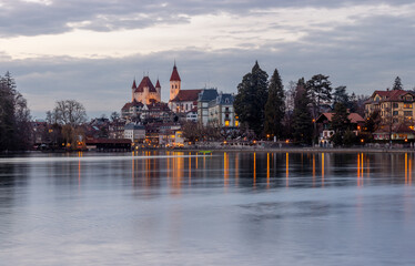 Thun city old town skyline with castle and church reflected in the aare river at night with illumination, canton bern switzerland.