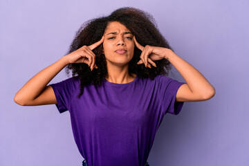 Young african american curly woman isolated on purple background focused on a task, keeping forefingers pointing head.