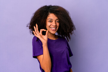 Young african american curly woman isolated on purple background cheerful and confident showing ok gesture.