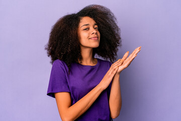 Young african american curly woman isolated on purple background feeling energetic and comfortable, rubbing hands confident.