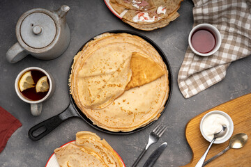 Delicious crepes on iron frying pan. Placed on table with various ingredients on side. Sin Pancakes. Breakfast table. With jam, cream, tea cup and tea pot. Flat lay. Top view. High quality photo