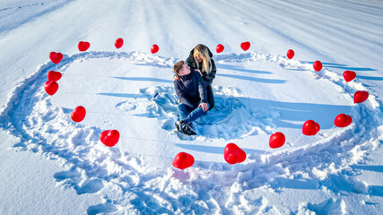 Walentynki, sesja narzeczeńska i walentynkowa w zimie na śniegu z czerwonymi serduszkami - obrazy, fototapety, plakaty