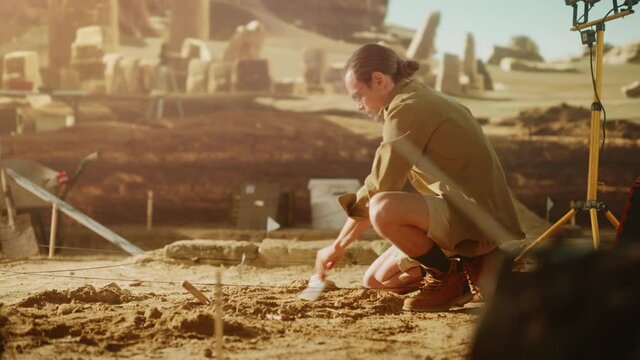 Archaeological Digging Site: Great Male Archeologist Work on Excavation Site, Carefully Cleaning, Lifting Newly Discovered Ancient Civilization Cultural Artifact, Historic Clay Tablet, Fossil Remains