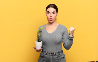 young pretty woman looking astonished in disbelief, pointing at object on the side and saying wow,...