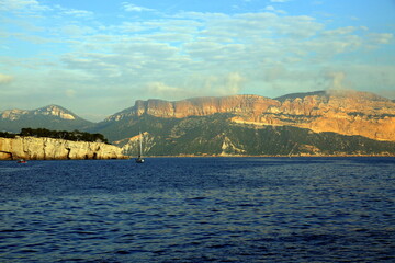 Fototapeta premium Sailboat on the blue sea with the background of the coast and mountains, Parc National des Calanques, Marseille, France