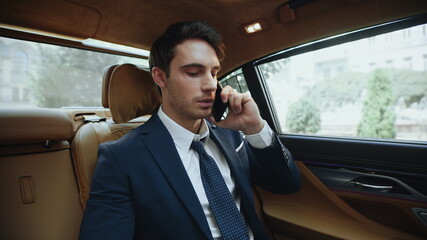 Portrait of handsome business man calling on smartphone in comfortable car.