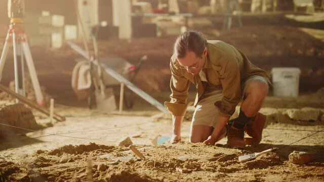Archaeological Digging Site: Great Male Archeologist Work on Excavation Site, Carefully Cleaning, Lifting Newly Discovered Ancient Civilization Cultural Artifact, Historic Clay Tablet. Slow Motion