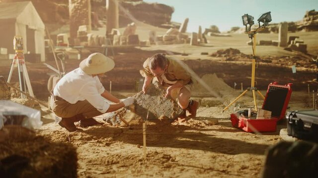 Archaeological Digging Site: Two Great Archeologists Work on Excavation Site, Carefully Cleaning, Lifting Newly Discovered Ancient Civilization Cultural Artifact, Historic Clay Tablet, Fossil Remains
