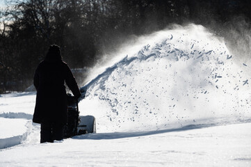 Worker using snow blower to make a path after heavy snow storm