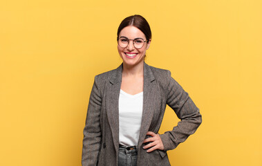 young pretty woman smiling happily with a hand on hip and confident, positive, proud and friendly...