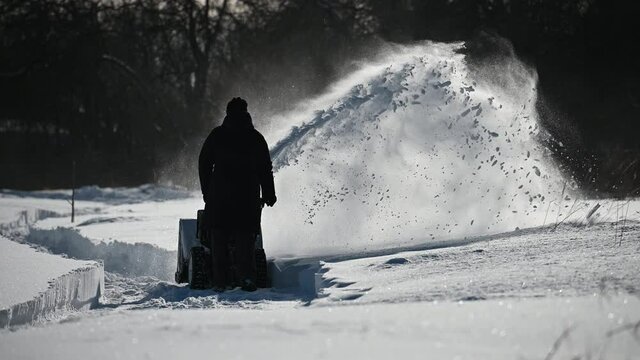 Person using snowblower to make a path after snow storm