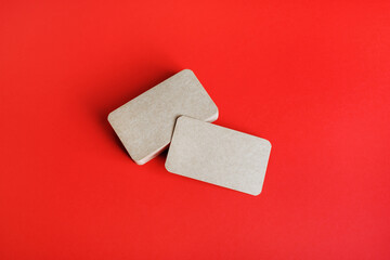 Photo of blank kraft business cards on red paper background. Mockup for branding identity. Blank corporate identity template.