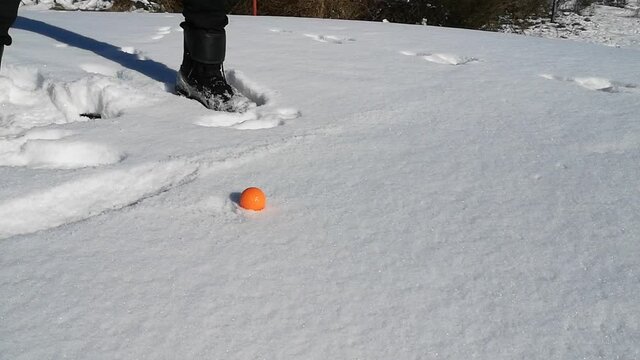 golfswing at wintertime with snow and a red ball