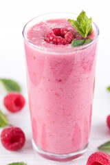 Raspberry smoothie with fruit and mint garnish on white background