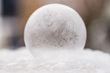 One frozen soap bubble on white snow with dark background