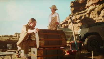 Archaeological Digging Site: Two Great Adventurers on Treasure Hunt Open Chest with Unspeakable Treasures, Celebrates Their Succers by doing High-Five. Ancient Civilization Hidden Gold Found