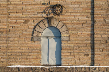 the door in the form of an arch is closed with a sheet of iron. old textured brick building