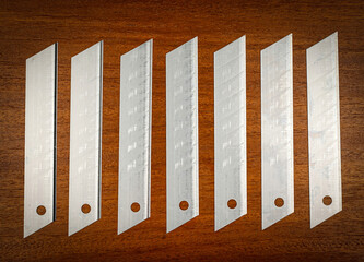 The blades are arranged in a row on a brown wooden background