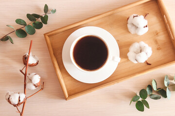 Cozy home flat lay. Tray with a cup of coffee, eucalyptus leaves and cotton flowers. Morning concept. Top view