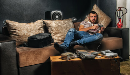 a bearded man lying in the console plays on the couch